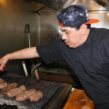 Vineyard Restaurant cook Alex Aguilar keeps his eyes on a grill full of New York steaks.